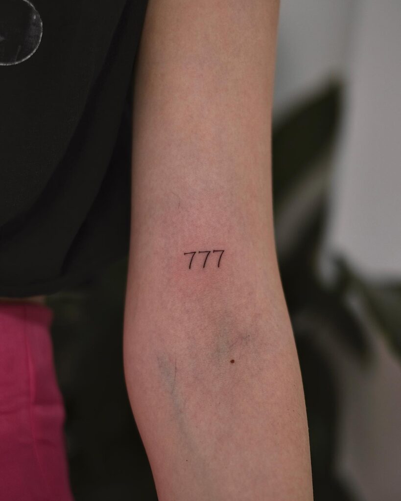 '777' Text Lettering Tattoo on the Above the Elbow: Divine Guidance 