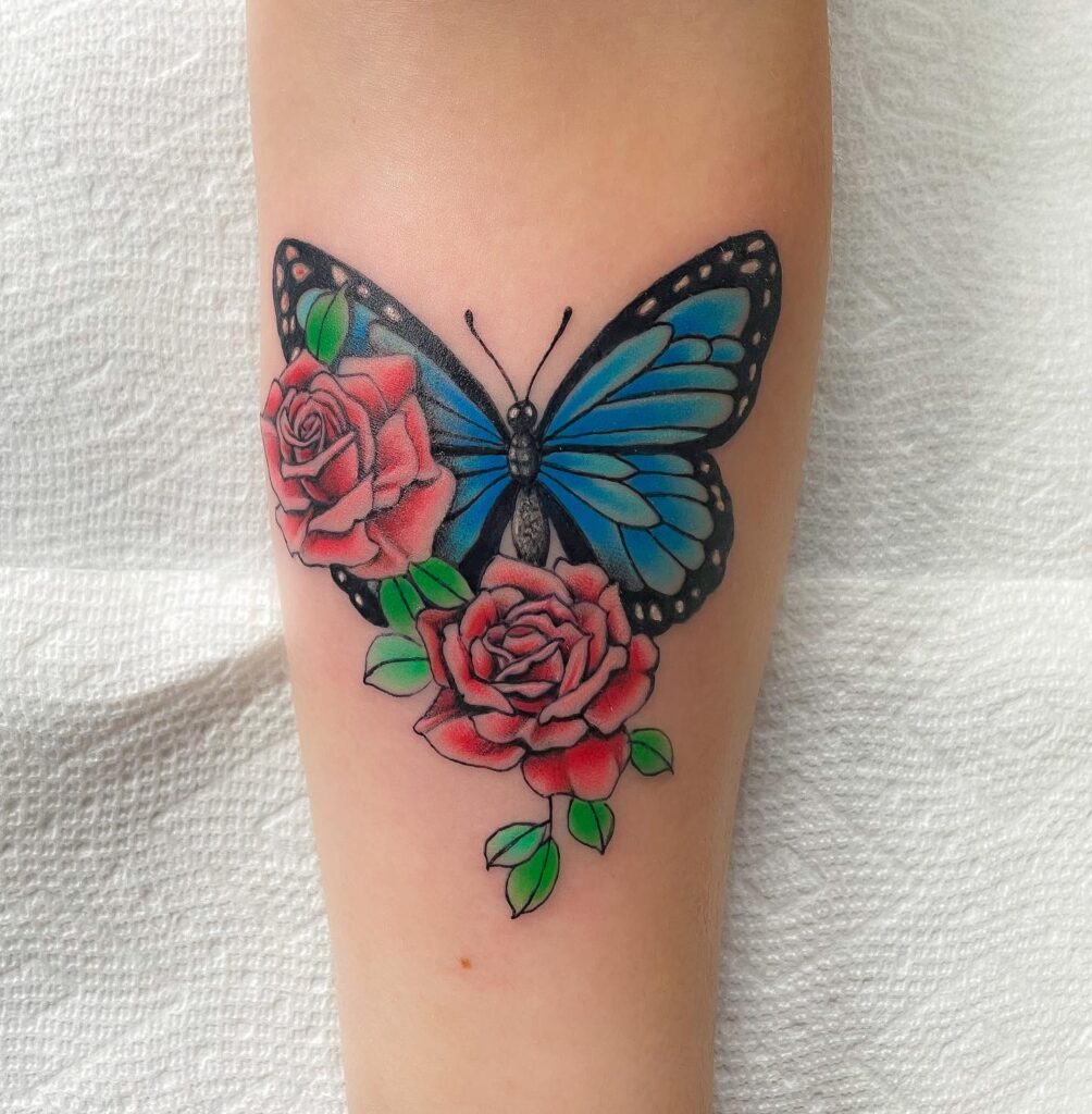 A fusion of elegance two roses and a blue butterfly tattoo on forearm