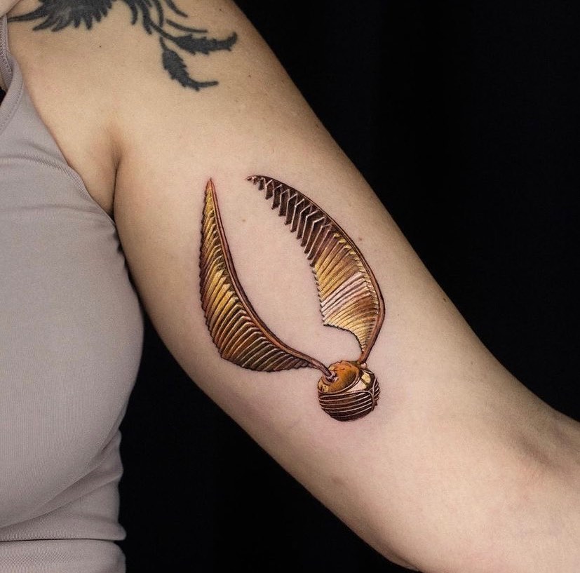 Colorful upper arm elegance golden snitch tattoo designs for females 