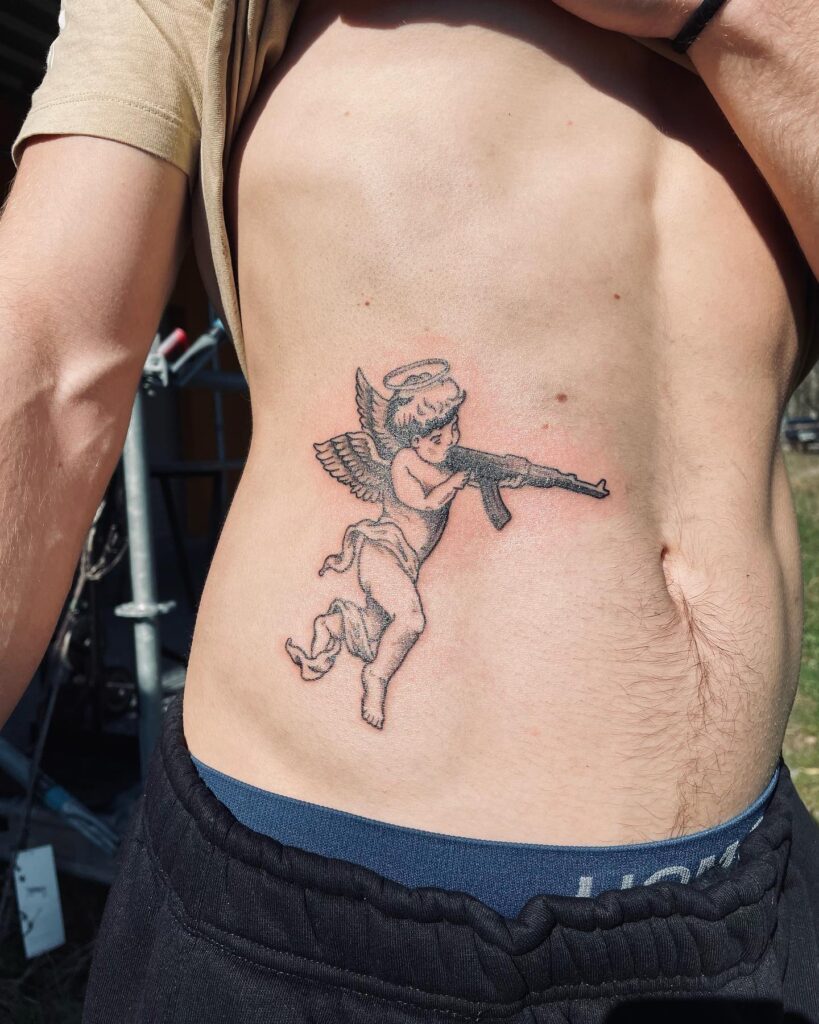 Cute angel with gun side stomach tattoo for men playful and bold ink 