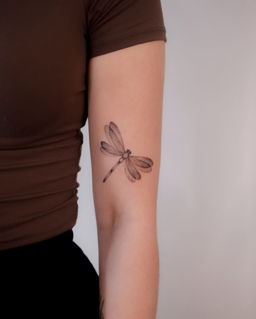 Ethereal Fine-Line Dragonfly Arm Tattoo with Soft Shading and Realism 