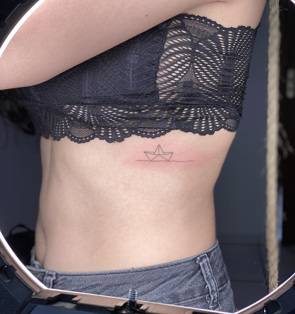 Finline paper boat outline tattoo on the rib minimalistic nautical rib tattoo 