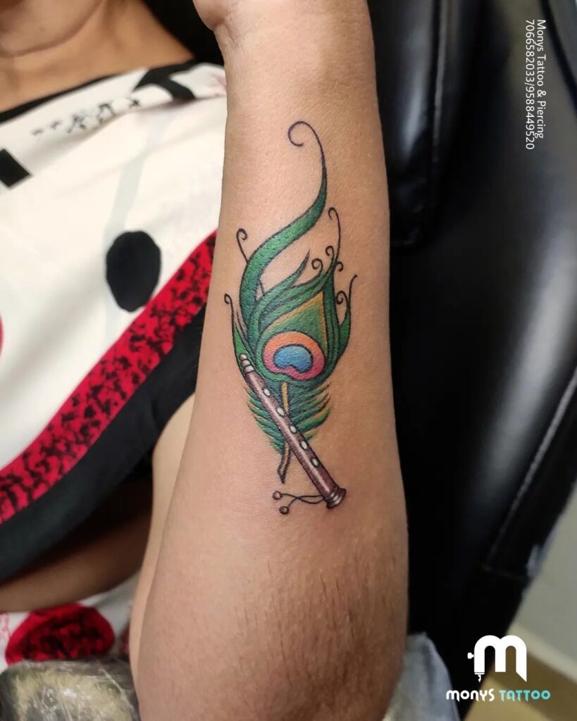 Flute and feathers colorful peacock feather tattoo with flute on the outer forearm for women 