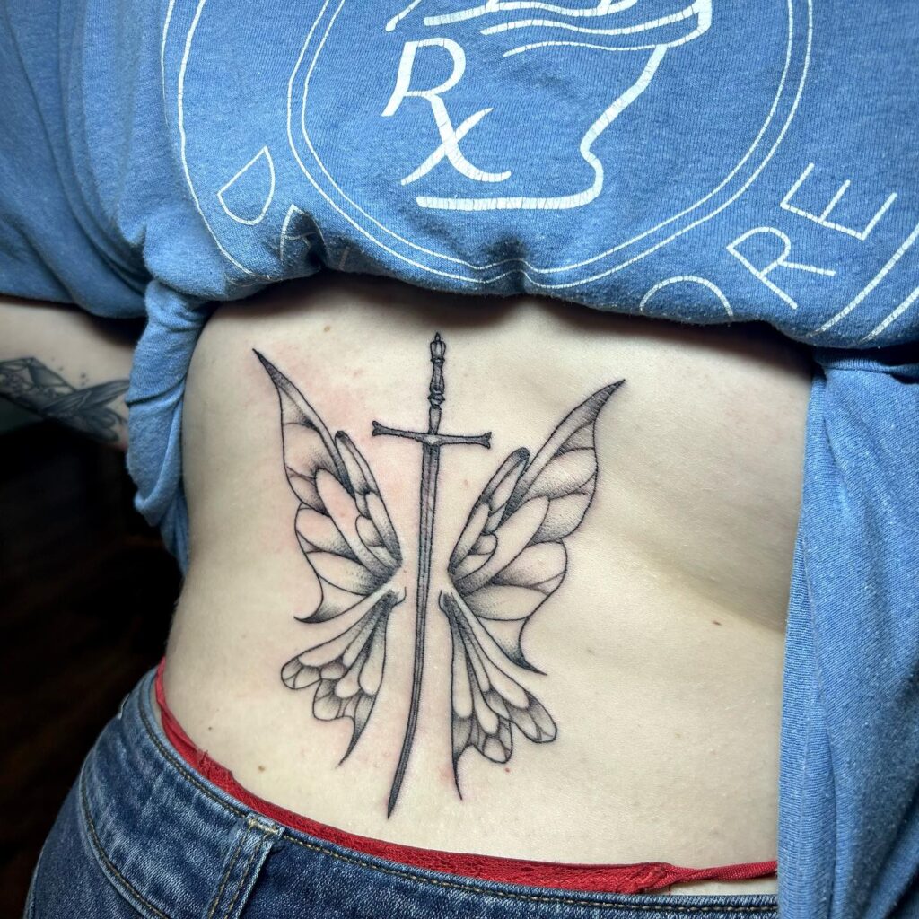 Illustrative Wing with Middle Sword Tattoo on the Lower Back: Fairy Tale Feathers 