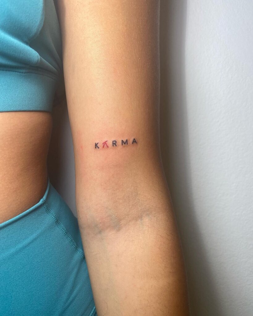 Karma text lettering tattoo above the elbow for girls 