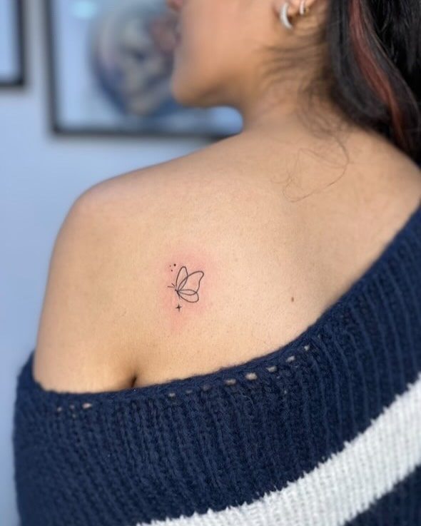 Minimalist butterfly tattoo on upper back near shoulder meaning 