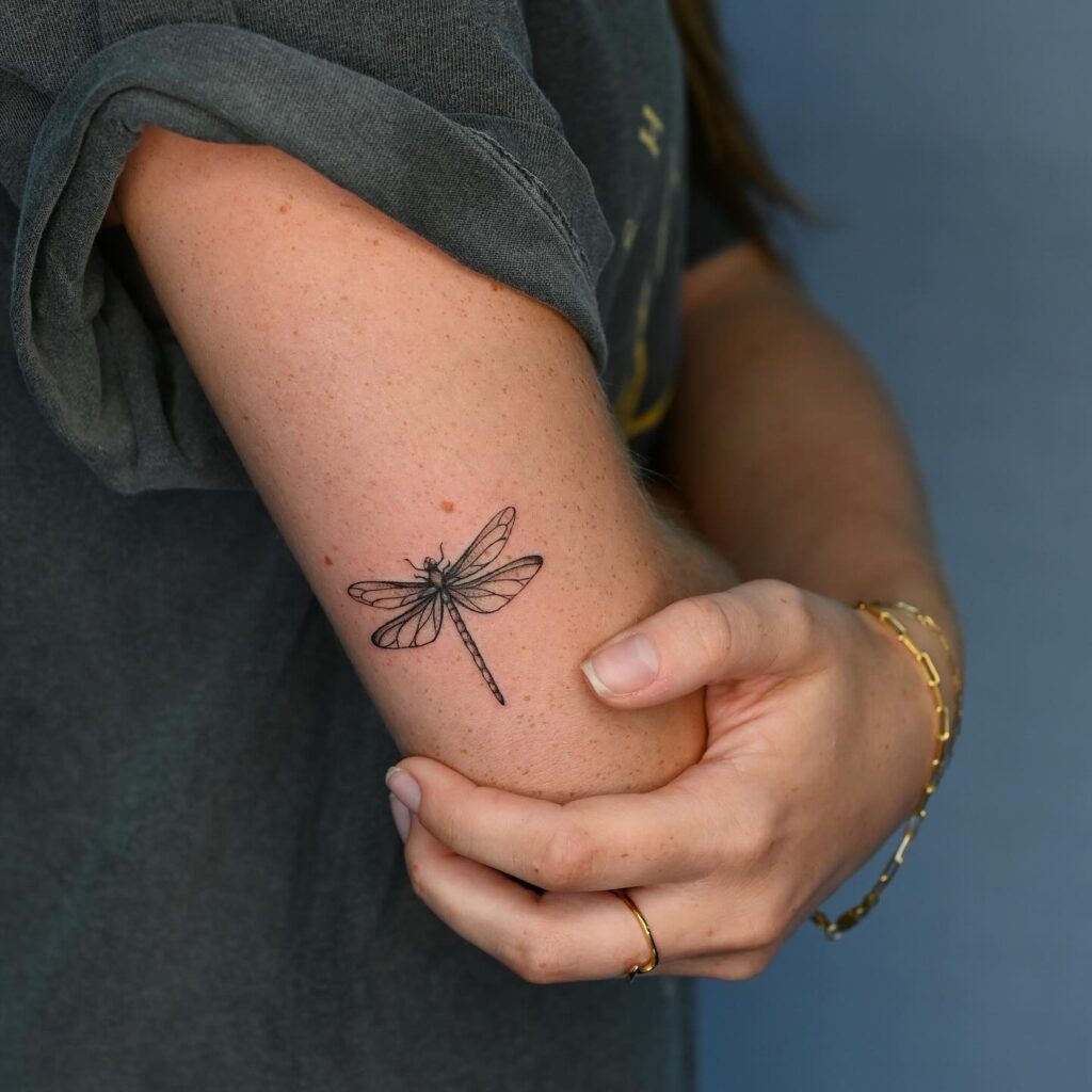 Minimalist Dragonfly Tattoo on Arm Symbolizing Transformation 