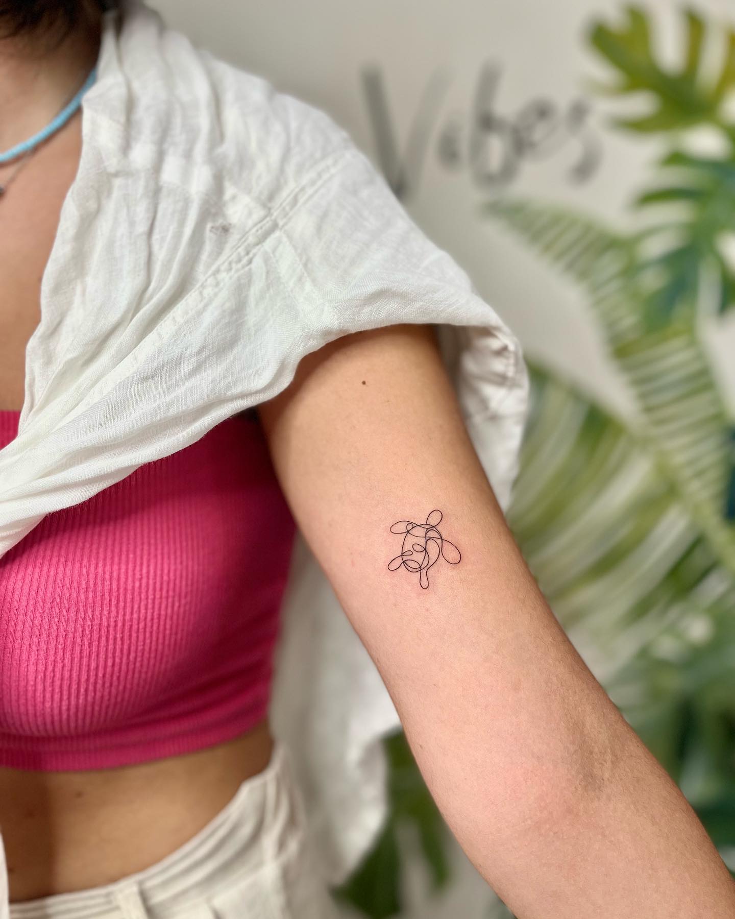 Minimalistic single-line sea turtle tattoo on upper arm 
