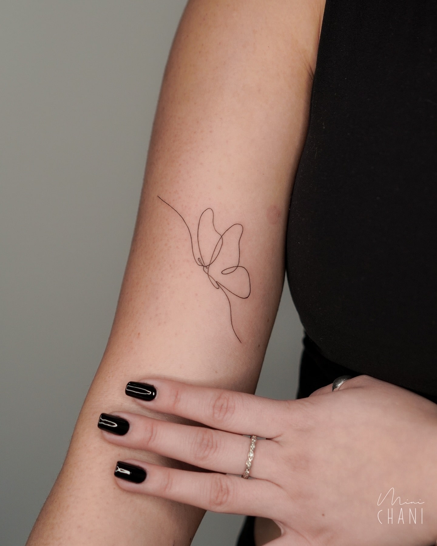 Single line butterfly tattoo on upper arm with minimalist symbolism 