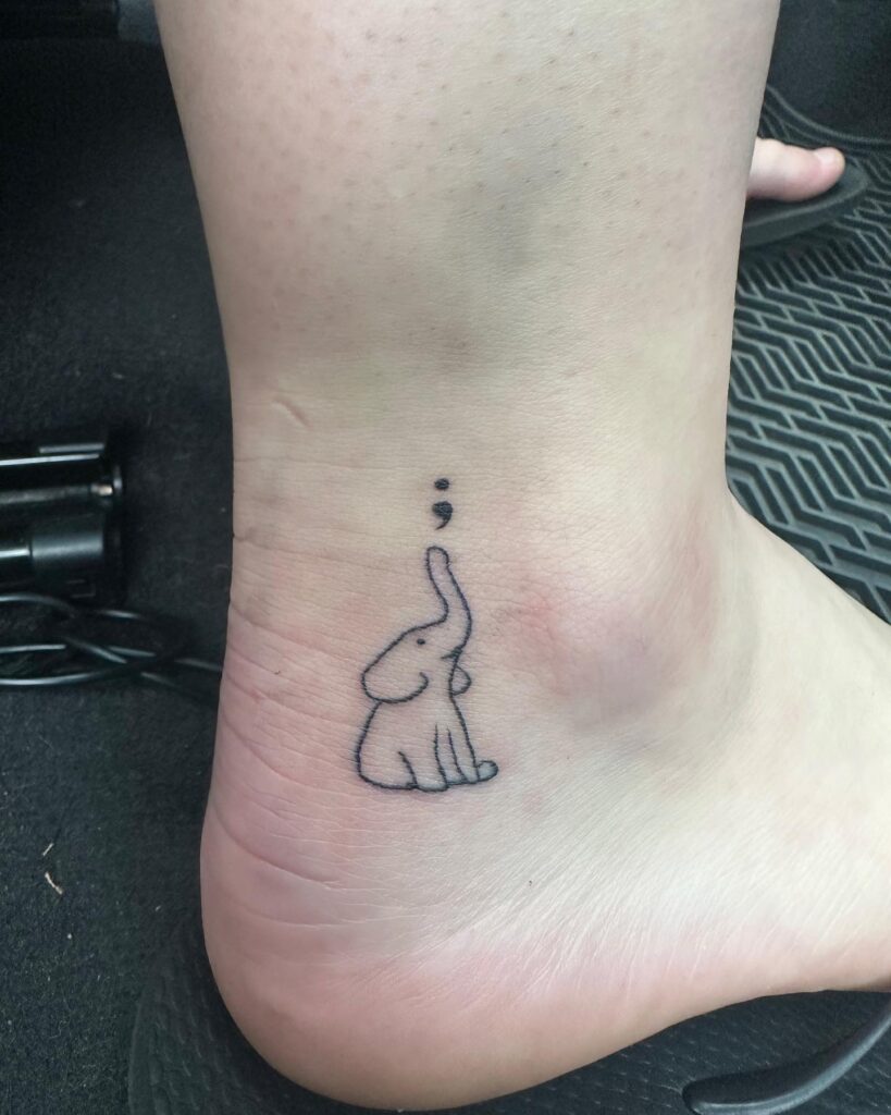 Small Baby Elephant Lifting Trunk Above a Semicolon Near the Ankle: Trunk of Hope 