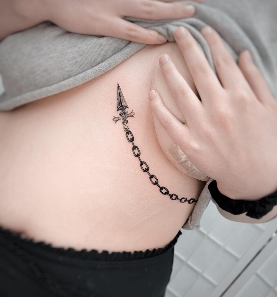 Striking dagger and chain rib tattoo with gothic and medieval elements 