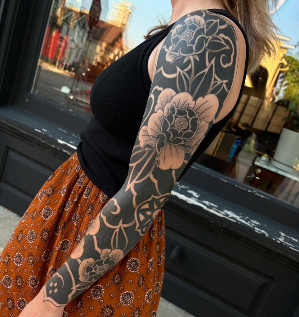 Striking floral blackwork tattoo sleeve with deep contrast and negative space for girls 