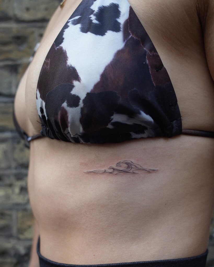 Tiny waves minimal tattoo on the rib: small and subtle rib wave ink 