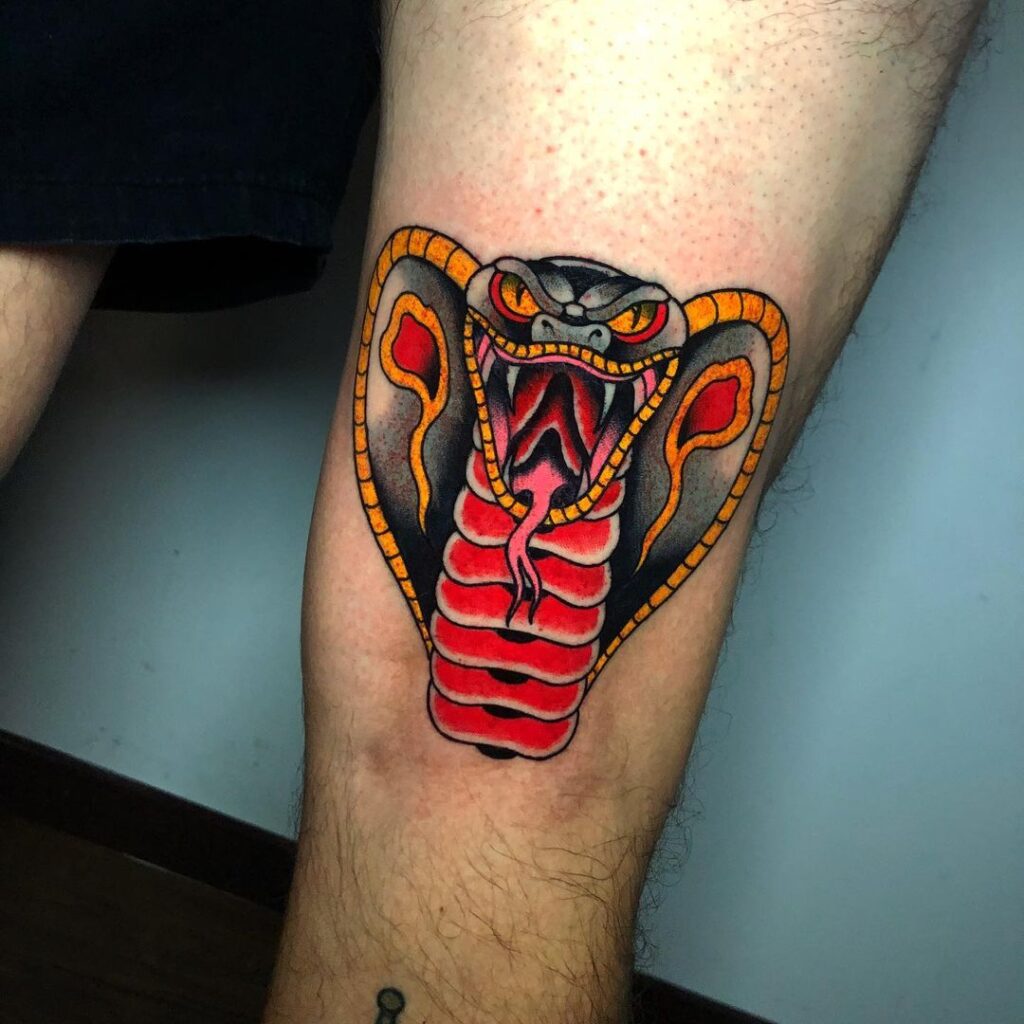 Traditional tattoo of cobra’s head old school ink with vibrant colors on knee 