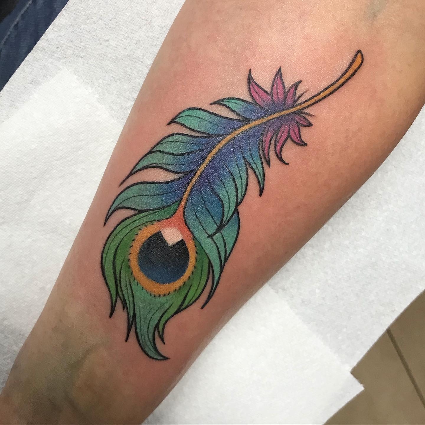 Vibrant and colorful peacock feather tattoo on hand