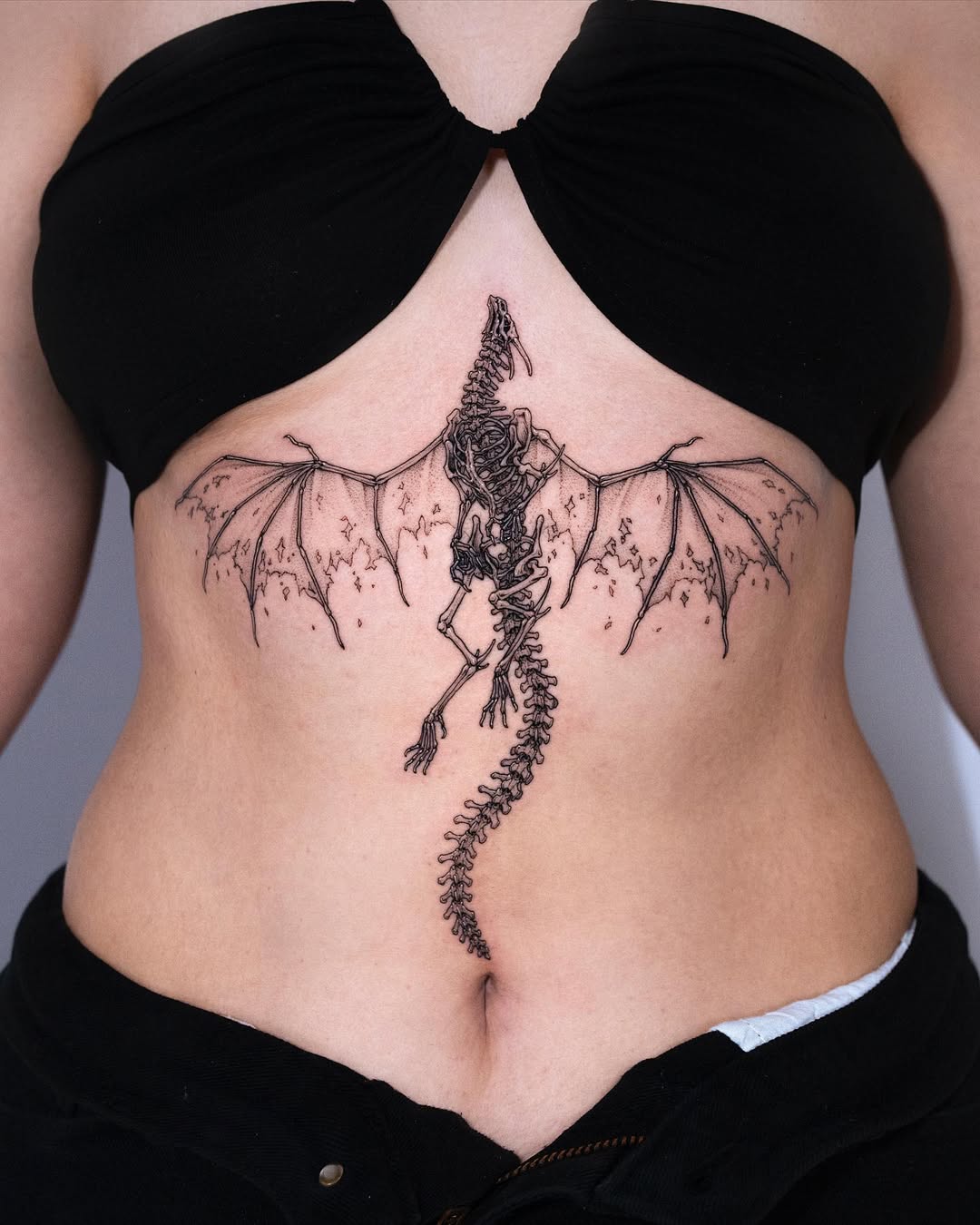 A stunning dragon skeleton underboob tattoo